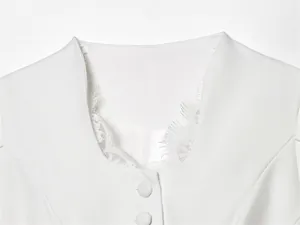 Detail shot of white women's blazer featuring delicate lace trim and covered buttons.