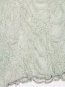 Detailed close-up of the delicate flocked lace fabric and wavy ruffled hemline