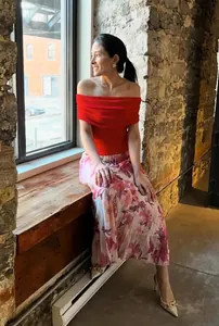 Lifestyle detail of an elegant off-shoulder red top and floral print midi skirt set