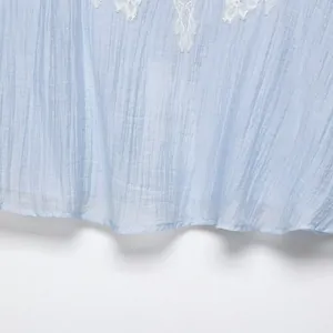 Elegant light blue lace top showing textured fabric and white floral embroidery detail