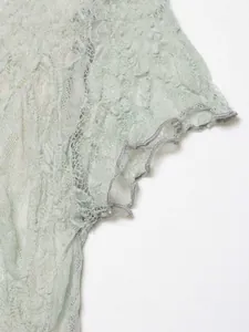 Macro view of delicate light green floral lace fabric with ruffled sleeve edge detail