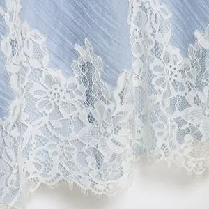 Elegant light blue crinkled fabric dress detail with intricate white floral lace hem