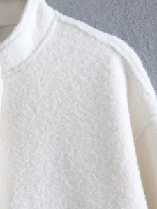 Detailed macro shot of white textured boucle fabric on a stand collar jacket shoulder