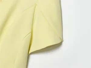 Close-up showing sleeve and seam detail on a pale yellow short-sleeved blazer jacket.