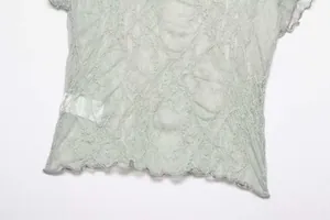 Close-up detail of the hem on a vintage light green lace t-shirt with ruffle edges.