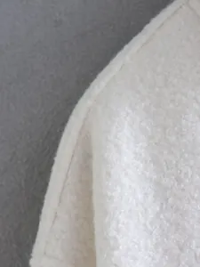 Detail showing texture of white fleece cardigan jacket with high quality seam stitch.