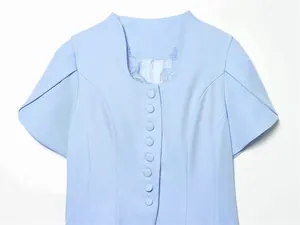 Close-up of light blue blazer top featuring lace patchwork neckline and matching covered buttons