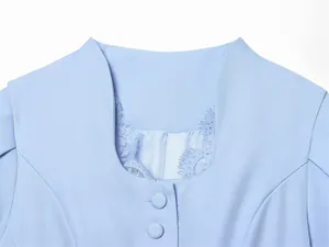 Detailed close-up of the elegant lace trim and covered buttons on a light blue blazer neckline