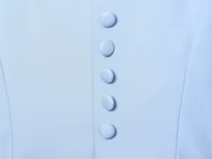 Macro view of textured light blue blazer fabric with matching fabric-covered buttons