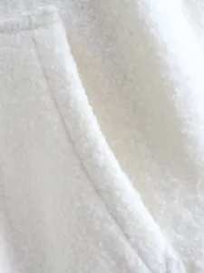 Macro detail shot of the white textured bouclé fabric pocket on a stylish autumn women jacket