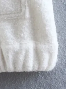 Detailed macro view showing the soft white sherpa fleece fabric and ribbed hem of a jacket