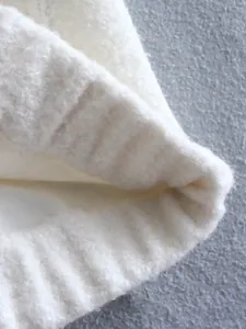 Close-up macro view of the soft white boucle knit texture and ribbed cuff detail