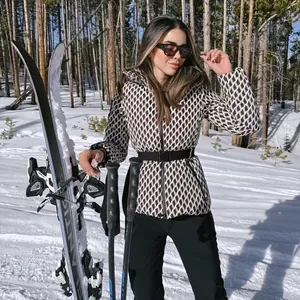 Women's hooded belted ski puffer jacket with diamond pattern in snowy outdoors.