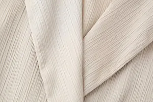 Detaillierte Makroaufnahme der eleganten Knitterstruktur des beigen Blazerstoffs.