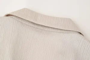 Detailansicht der plissierten Stoffstruktur und des Kragens eines beigen Damenblazers