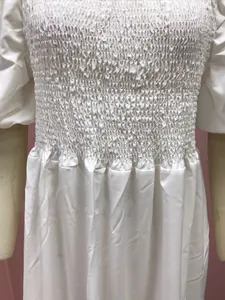 Close-up detail of the elastic smocked bodice on a white off-the-shoulder maxi dress