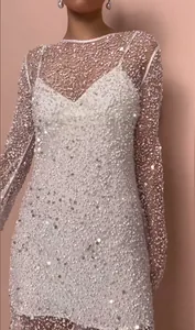 Detailansicht eines zweiteiligen Paillettenkleides mit weißem Unterkleid und Perlen
