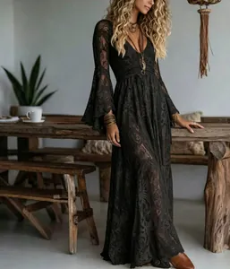 Elegant black lace maxi dress with deep V-neck and bell sleeves in a rustic indoor setting