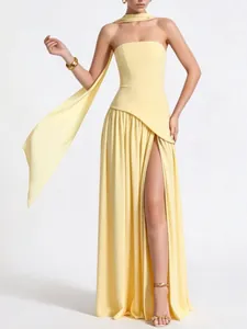 Elegant strapless light yellow evening gown with a high slit and flowing neck scarf detail.