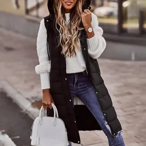 Dettaglio di un lungo gilet trapuntato nero con cappuccio su un maglione bianco