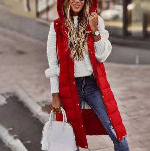 Lungo gilet imbottito rosso con cappuccio indossato sopra un maglione bianco all'aperto