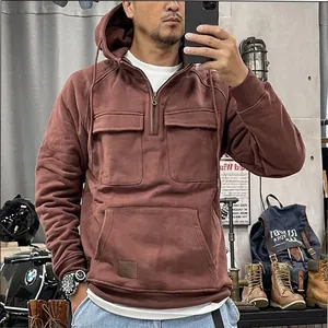 Detail of men's rust red workwear half-zip hoodie with multiple front cargo pockets.