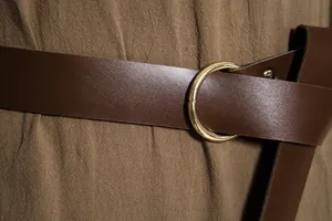 Λεπτομέρεια μεσαιωνικής καφέ δερμάτινης ζώνης με χρυσή μεταλλική αγκράφα σε σχήμα κρίκου.