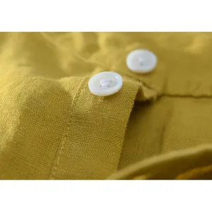 Detailed macro shot of white buttons and premium yellow linen cotton shirt fabric texture
