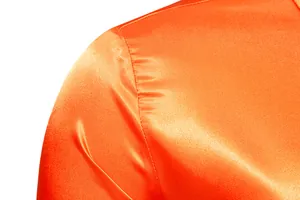 Detalle macro del hombro de una camisa de satén naranja brillante con tela y costura