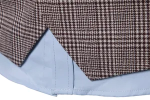 Detailed close-up of brown houndstooth vest hem showing stitching and blue shirt layer.