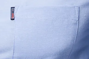 Close-up of light blue Oxford fabric shirt pocket with small logo tag