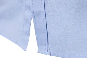 Macro view of the side slit and reinforced stitching on a light blue Oxford cloth shirt
