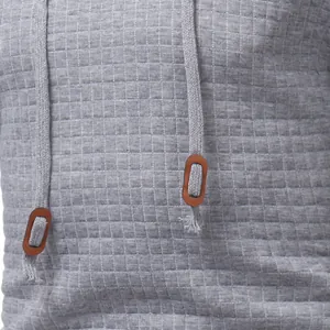 Detailed macro view of gray men's pullover hoodie featuring diamond quilted fabric