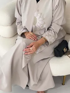 Detail view of sunflower embroidery and pearl accents on elegant beige open robe