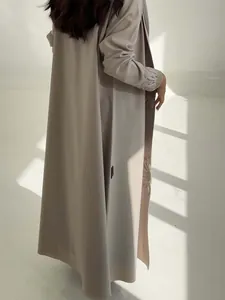 Elegant light grey abaya cardigan featuring sunflower embroidery in a sunlit studio setting