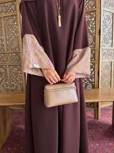 Detail showing the intricate printed batwing sleeves of an elegant maroon abaya