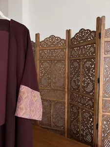 Close-up of elegant burgundy robe with patterned sleeve detail and wooden screen background.