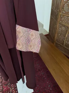 Detail of a burgundy long abaya showing elegant geometric printed wide sleeve cuff.