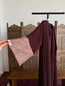 Detailed view of maroon robe's printed cuff and brand tag for elegant women.