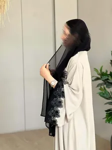 Detailed side view of elegant beige abaya featuring exquisite black floral embroidery