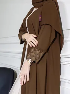 Elegant dark brown abaya with intricate gold sleeve embroidery and flowing fabric