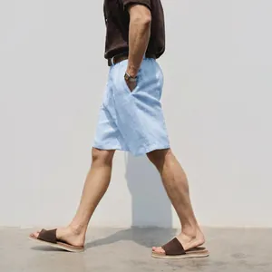 Full side view of a man walking in light blue breathable linen shorts for summer