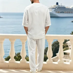 Vista posteriore di un uomo con un completo in lino bianco su un balcone al mare