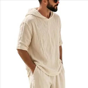 Modèle portant une chemise homme en lin à capuche, coupe ample, blanc cassé d'été.