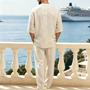Vista posteriore di un uomo in abito di lino beige su un balcone con vista mare