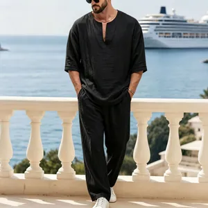 Set casual in lino nero da uomo con top con scollo a V e pantaloni larghi su un balcone estivo.