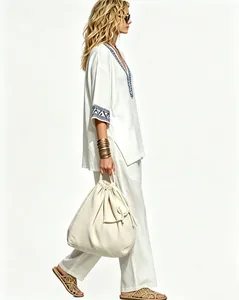 Detail view of women's bohemian white linen two-piece set with blue embroidered trim