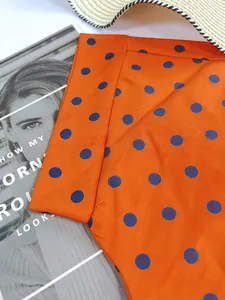 Close-up detail showing the vibrant orange and purple polka dot print on Polo shirt fabric