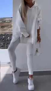 Close-up showing the fit of a white oversized hooded sweatshirt and matching leggings set.
