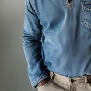 Close-up of men's blue denim shirt featuring a half-zip collar and chest pocket detail.